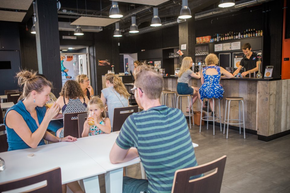 Familie met kindje drinken een glaasje in de hostel bar