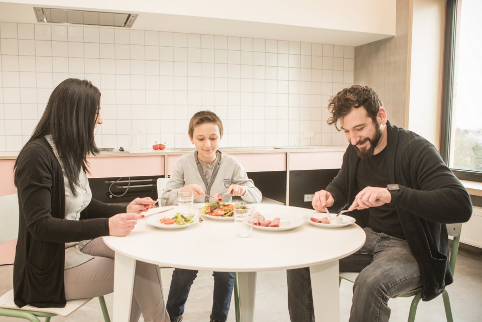 Famille en train de manger dans la cuisine commune